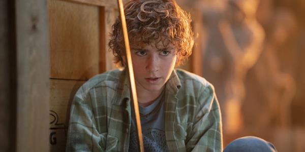 Percy Jackson has an intense look on his face while holding up his sword.