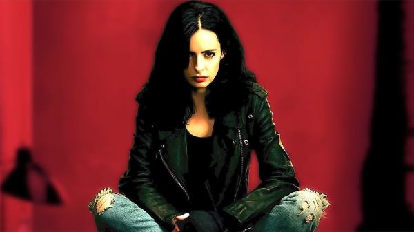 Krysten Ritter as Jessica Jo<em></em>nes sitting with red background