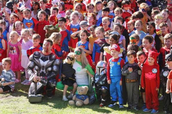 Hillcrest Primary School students dressed as their favourite hero in support of childhood cancer families for Hero Hunter Day, pictured are the school's students gathering for a group photo with Hunter Madden's parents Dave Madden, Kate Bettenay and his sister Phoebe, 3, and brother Zac, 8, in the foreground. Hero Hunter Day celebrates the courage of kids fighting cancer, it also ho<em></em>nours the life of Perth schoolboy Hunter Madden, a student at Hillcrest Primary, who heroically fought leukaemia for five years. Hunter sadly died at eight years old in 2021. Danella Bevis