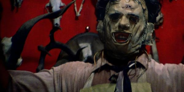 Leather face stands by animal skulls in The Texas Chainsaw Massacre